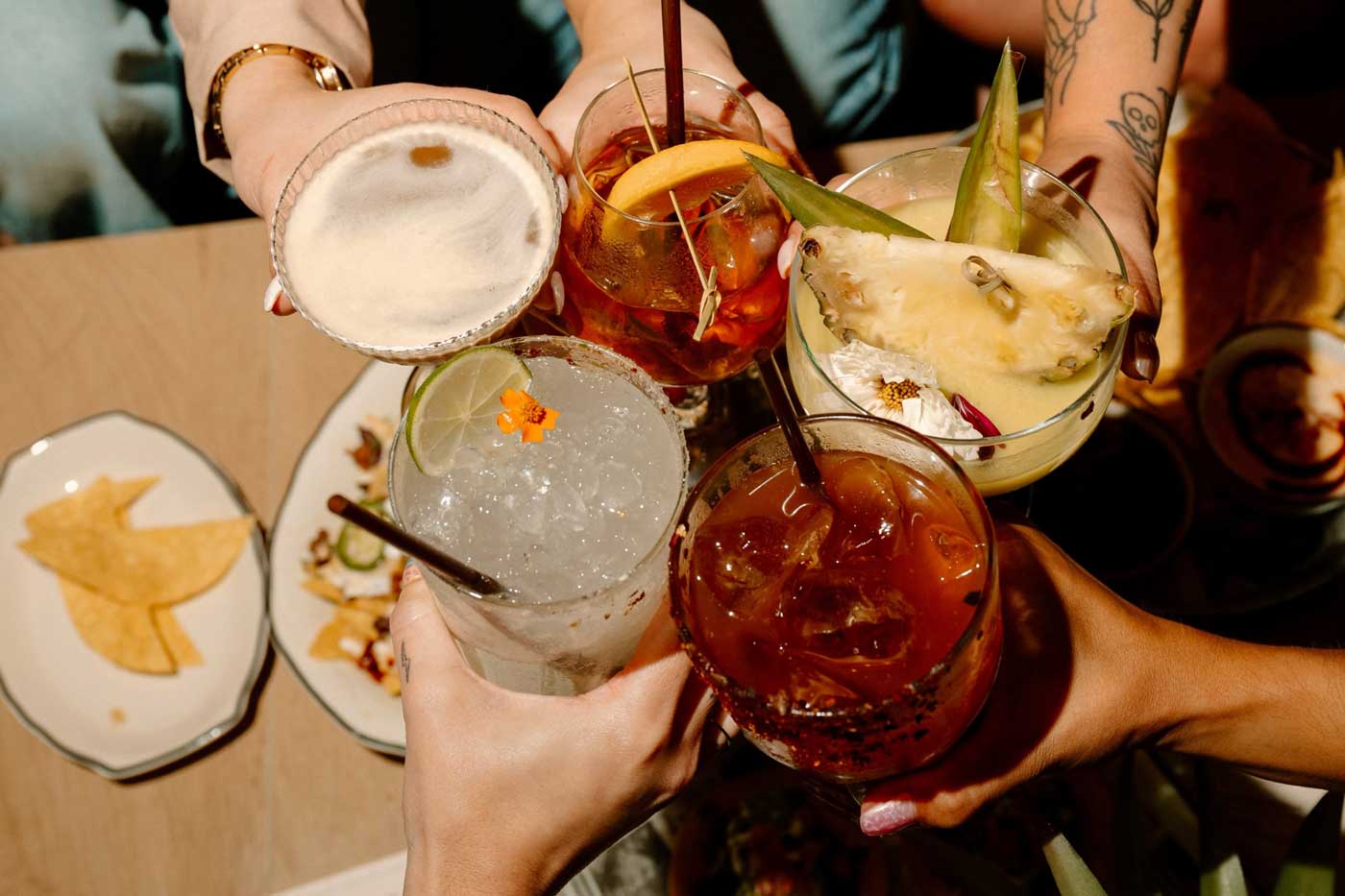 Hands toasting cocktails over chips at Sugar, the Latin and Mediterranean restaurant returning to Park Street