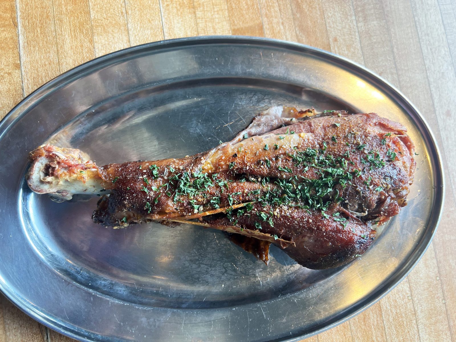 A roasted turkey leg on a steel platter at Uncle Red’s, topped with chopped herbs