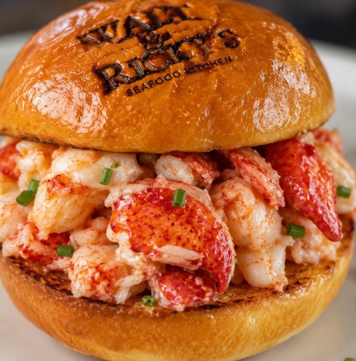A lobster roll in a toasted bun stamped Wally & Ricky’s Seafood Kitchen