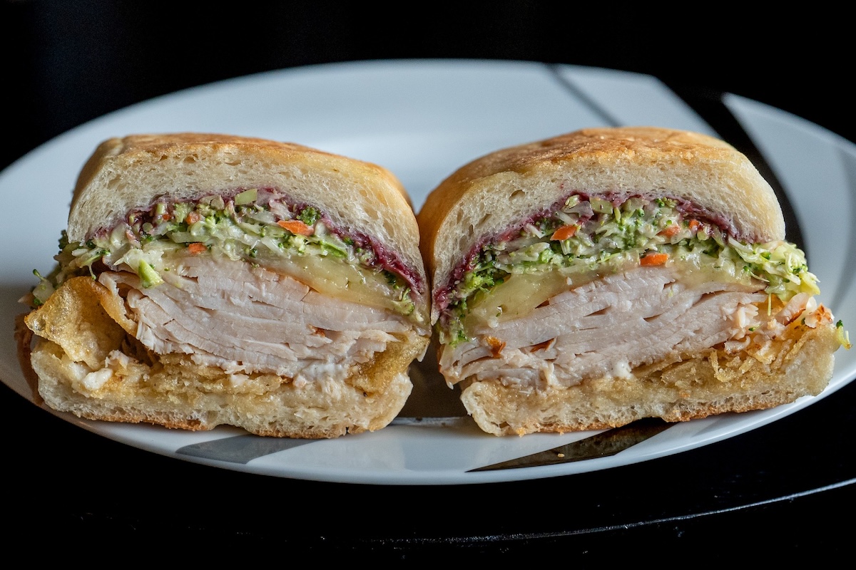 A Better Half sandwich cut in half, showing slaw, roasted meat, and a magenta spread