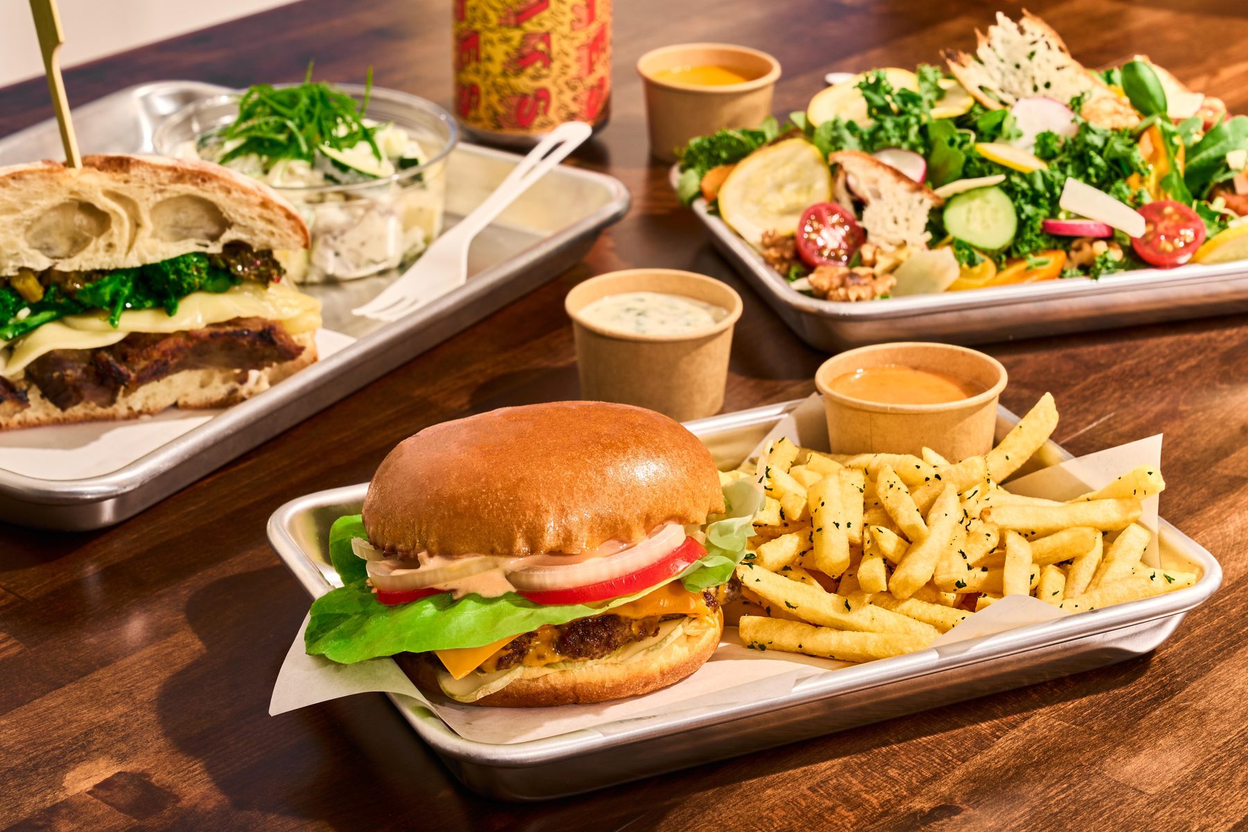 Trays at the Mess Hall in the Presidio: smash burger, porchetta sandwich, and a walnut salad